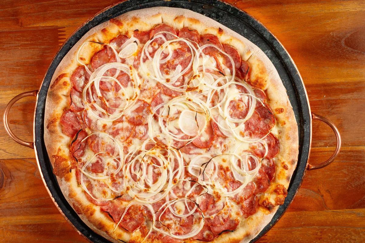 Pizza inteira fotografada de cima, ainda saindo do forno