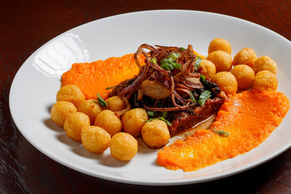 Carne desfiada sobre purê de cenoura com batatas