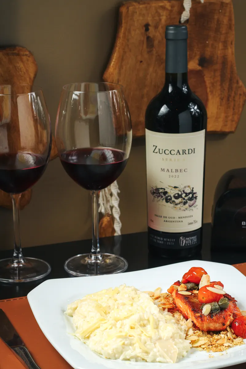 Prato de salmão com taças e garrafa de vinho na mesa