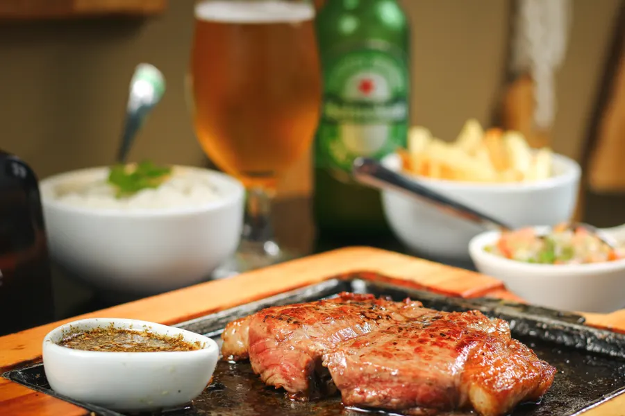Carne na pedra quente com cerveja, arroz e fritas