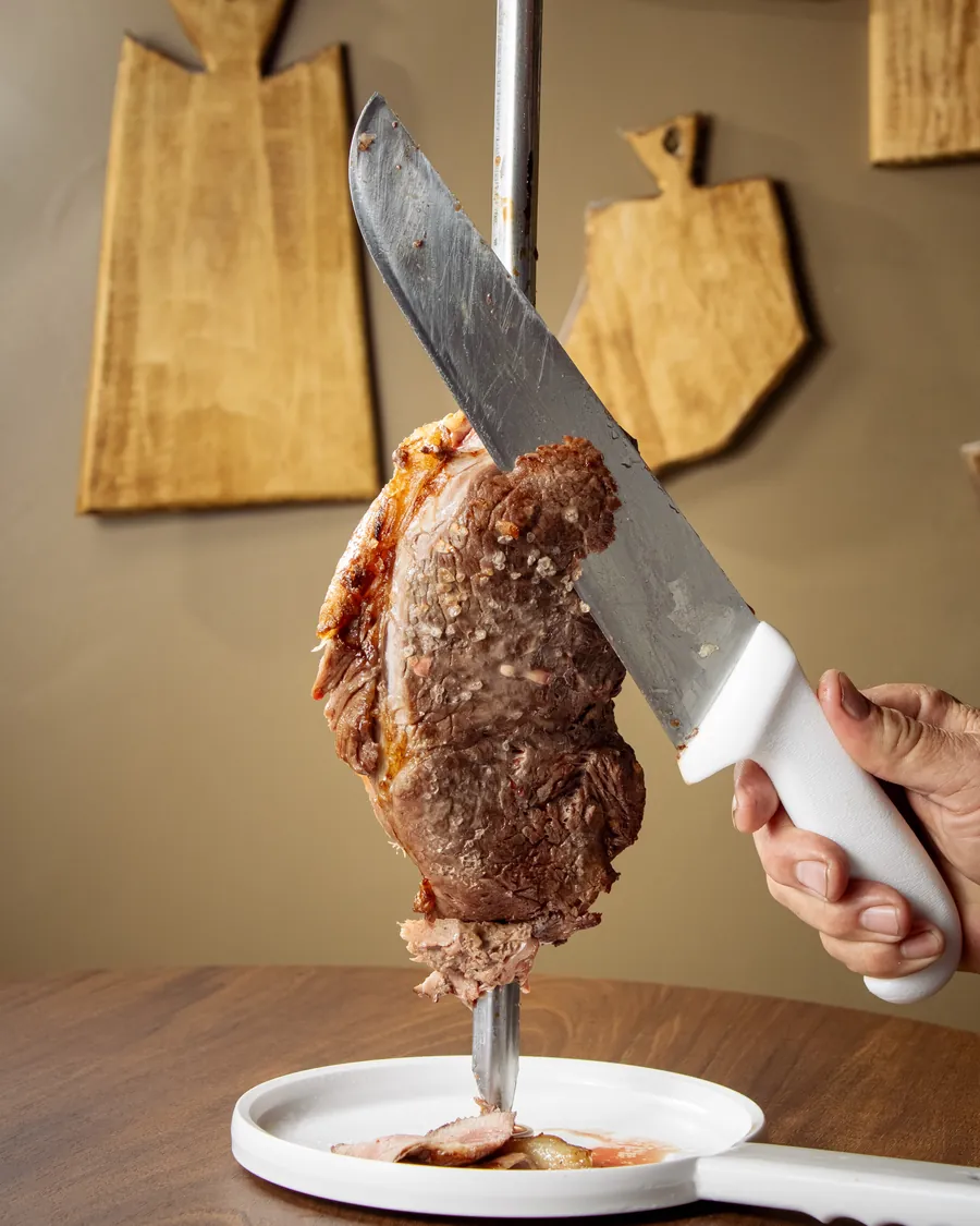 Picanha no espeto sendo fatiada na hora