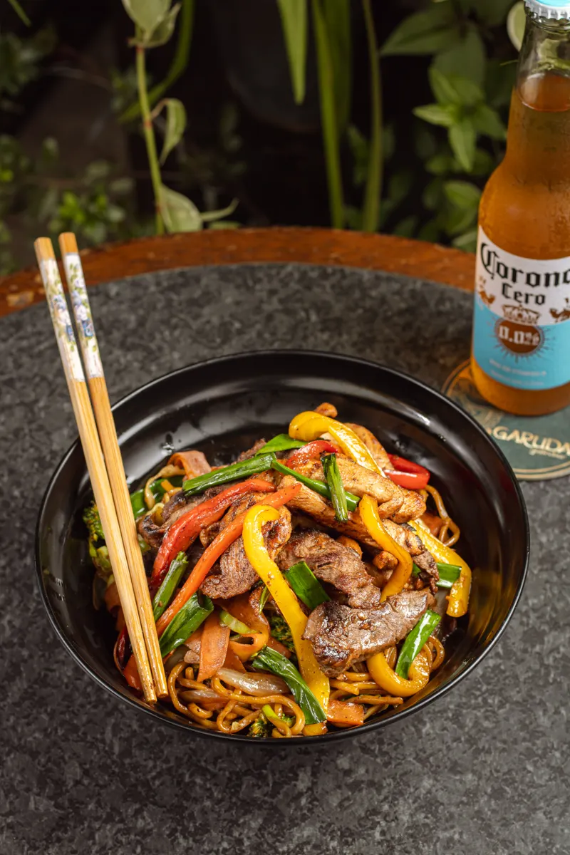 Yakisoba com tiras de carne e pimentões segurado com hashi