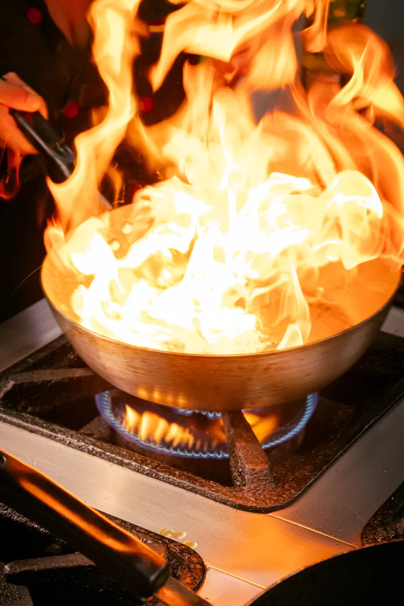 Chama alta na panela durante o preparo na cozinha do Garuda